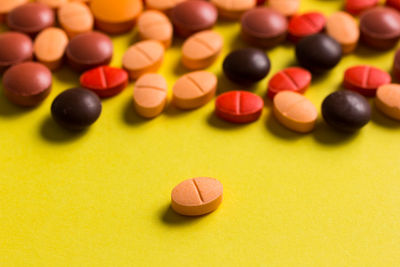 Close-up of colorful pills on yellow table