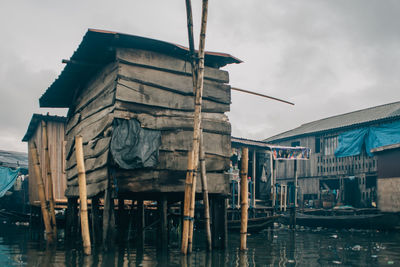 Wooden posts on house by building against sky