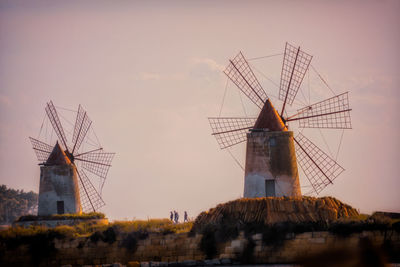 Low angle view of windmills against sky during sunset