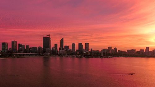 City by sea against cloudy sky during sunset