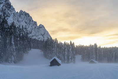 Snow covered landscape against sky during sunset