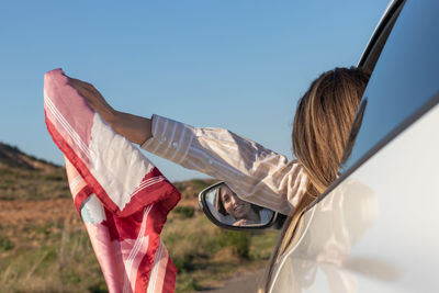 Low angle view of woman holding american flag against clear sky