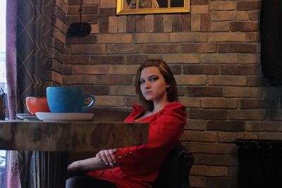 Portrait of young woman standing against wall