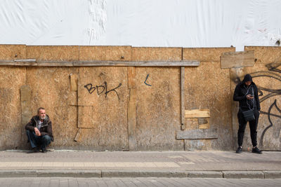 Full length of men on street against wall