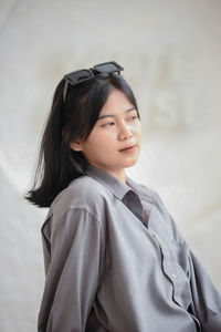 Portrait of young woman standing against wall