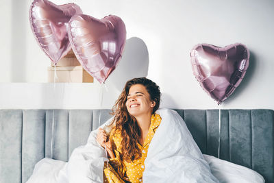 Portrait of young woman standing on bed at home