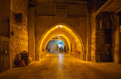 Illuminated street amidst buildings in city