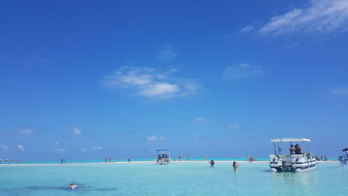 People on boats in sea against blue sky