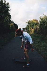 Full length of man skateboarding on road during sunset