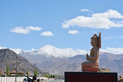 Statue on snowcapped mountains against sky