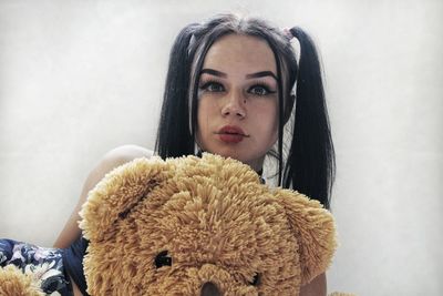 Portrait of beautiful woman with teddy bear against wall