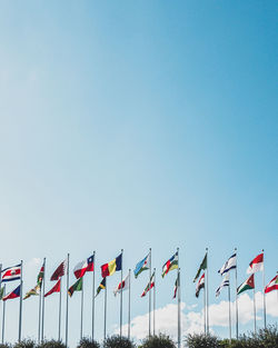 Low angle view of flags against clear blue sky