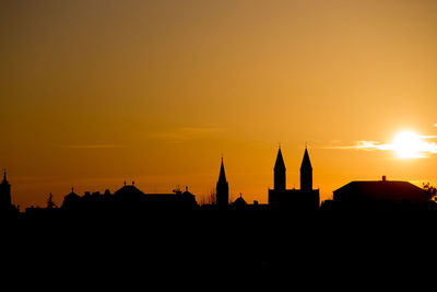 Silhouette buildings against orange sky during sunset