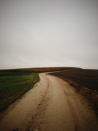 Road amidst field against sky