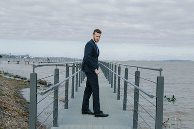 Full length of man standing on railing against sea