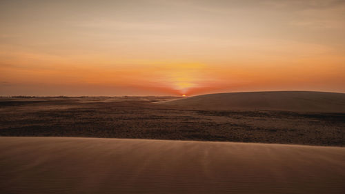 Scenic view of desert against sky during sunset