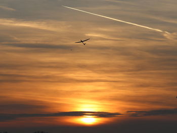 Low angle view of silhouette airplane against sky during sunset