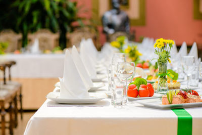 Long served table with plates, glasses, napkins, chairs and dishes