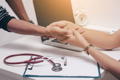 Midsection of woman holding hands on table