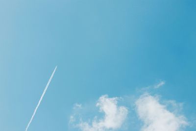 Low angle view of vapor trails in blue sky