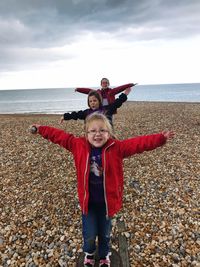 Sisters arms outstretched standing in row at beach