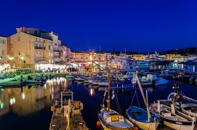 Boats moored at harbor in city at night