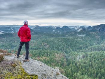 Cold misty day on trail. man take a moment on cliff edge for watch silent foggy countryside.