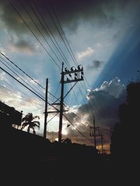 Low angle view of electricity pylon against cloudy sky