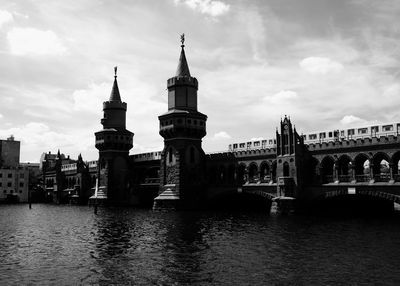 Bridge over river by buildings against sky in city