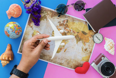 Cropped hands of man holding model airplane over map at table