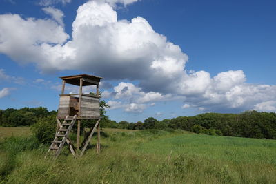 Hunters seat on field against sky