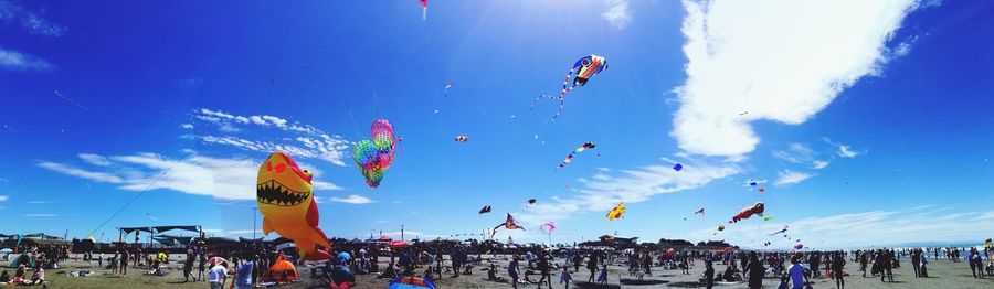 Low angle view of people at beach against blue sky