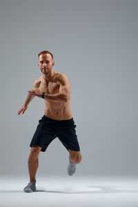 Full length of man exercising on white background