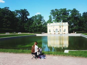 Woman sitting on seat against trees