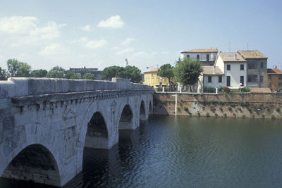 Arch bridge over river against buildings in city