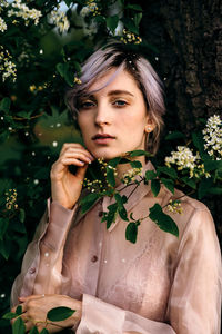 Portrait of young woman standing by plants at park