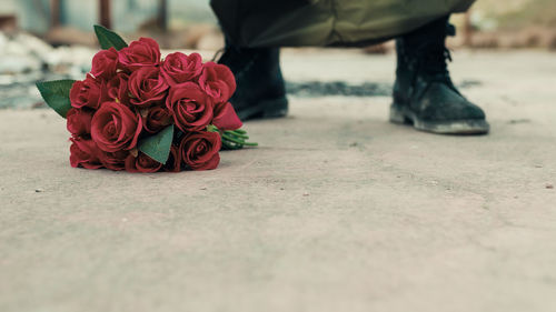 Man leans bunch of red flowers on the ground