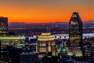 Illuminated buildings in city during sunset