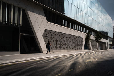 Man walking on street against modern buildings in city