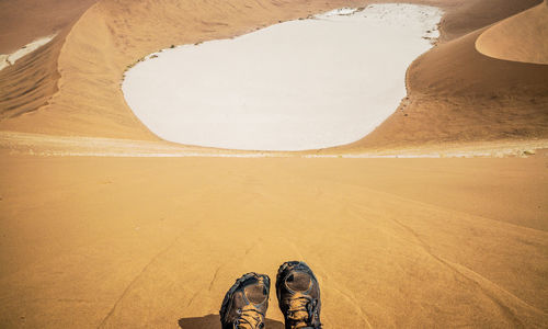 Low section of man sitting on sand