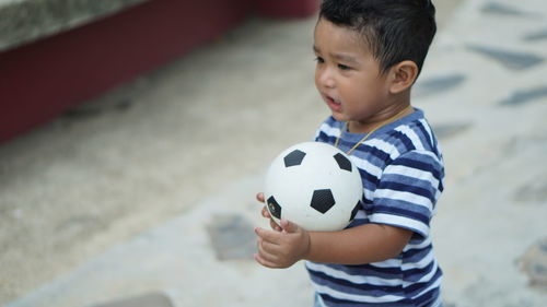 High angle view of baby boy playing with soccer ball on floor