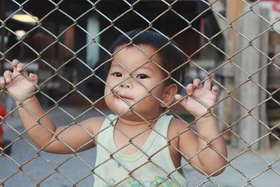 Portrait of cute baby girl seen through fence