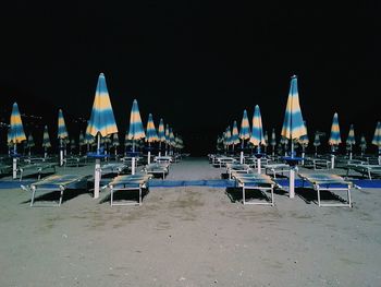 Lounge chairs with parasol at beach against clear sky at night