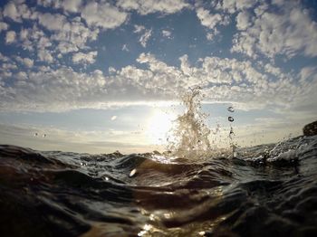 Sea waves splashing on shore against sky