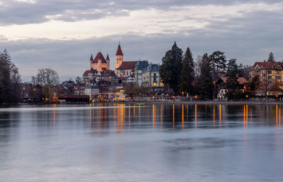 Thun city old town skyline with castle and church reflected in river at night switzerland.