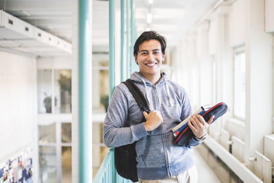 Portrait of confident young male student in corridor of university