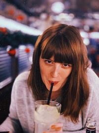 Portrait of woman drinking while sitting at restaurant