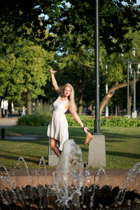 Beautiful woman with arms outstretched standing on footpath at park