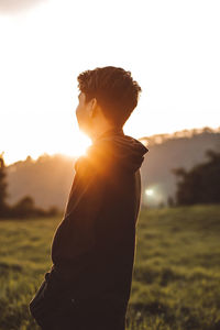 Man standing on field against sky during sunset