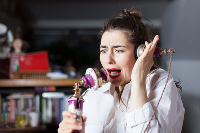 Close-up of worried woman talking on old-fashioned landline phone at home